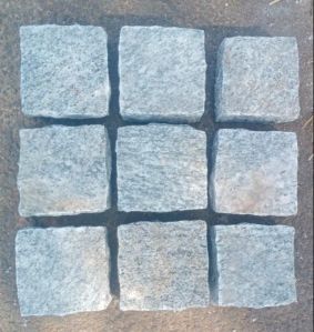 White hand cutting granite cobblestone